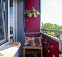A balcony garden of a 2-room apartment in Trnava with plants and decorative cushions.