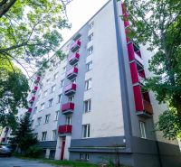 An apartment building with red balconies and greenery in Trnava.