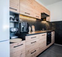 A kitchen in a 2-room apartment with practical cabinets and dark tiles.