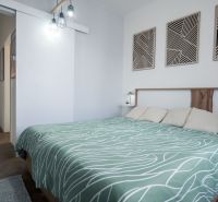 Bedroom in a 2-room apartment with decorative panels and wood-patterned flooring.