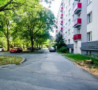 A view of the street in Trnava near an apartment building with a 2-room apartment and parked cars.