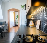 A kitchen in a 2-room apartment with black tiles and decorative flooring design.