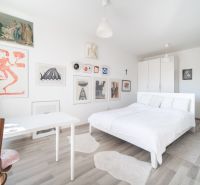 Bedroom of a two-room apartment with art on the walls and a floor with a wooden decor.