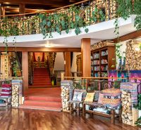 Interior of a family house with decorative trees, wooden-patterned flooring, and colorful cushions.