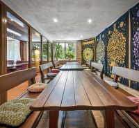 A dining room in a family house with benches and colorful textile decorations on the wall.