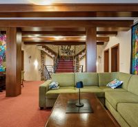 Living room in a family house with colorful textiles, a green sofa, and wooden decorations.