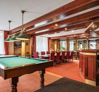 Interior of a family house with a billiard table, wooden decor, and a dining table.