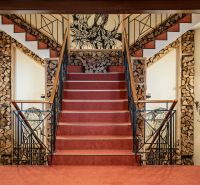 A staircase with carpet, wooden decorations, artistic walls in a family house.
