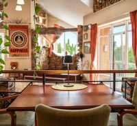 A table with a lamp, a plant, and colorful accessories in a family house with a wood-patterned floor.