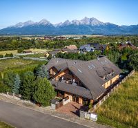 A family house in Veľká Lomnica, surrounded by mountains, in the middle of a green landscape.