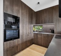 A kitchen in a 3-room apartment with dark wood decor and built-in appliances.