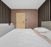 A bedroom in a three-room apartment with striped wallpaper and neutral furnishings.