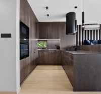 A kitchen with a dark decor and a wooden decor floor in a three-room apartment.