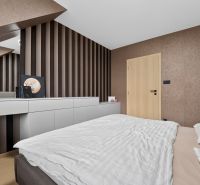 A bedroom with a mirror, striped wallpaper, and a wooden decor floor in a 3-room apartment.