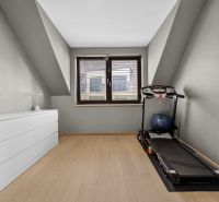 A gym in a 3-room apartment with a treadmill and a wooden decor floor.