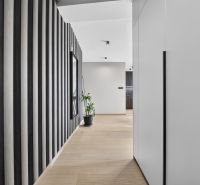 A hallway in a 3-room apartment with a wooden decor floor and vertical black-and-white tiles.