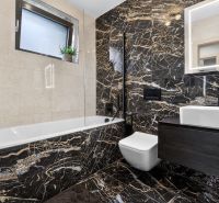 A luxurious bathroom with a bathtub and dark marble tiles in a 3-room apartment.
