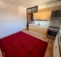 A kitchen with a wooden decor floor and a red carpet in a 3-room apartment.
