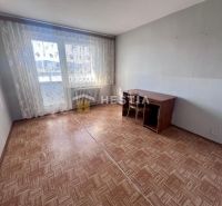 A room in a 3-room apartment with a wooden decor floor and a table by the window.