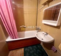 A bathroom in a 3-room apartment with a bathtub and a pink curtain, a white sink, and a cabinet.