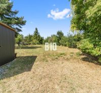 A garden at a family house in Podhájska with a lawn and a wooden shelter.