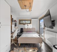 Bedroom with a bed and a table in a family house with a wooden decor floor.