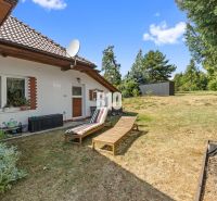 A family house in Podhájska with a terrace, sun loungers, and a satellite dish on a grassy plot.