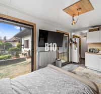 Interior of a family house with a bed, TV, kitchenette, and a view through a large window.