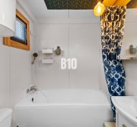 A bathroom in a family house with a bathtub, a sink, and a colorful shower curtain.
