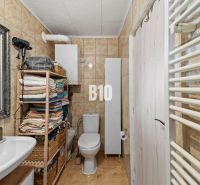 Bathroom in a family house, with a bathtub, sink, and tiles in natural shades.