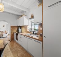 A kitchen in a family house with white cabinets and a wood-patterned floor.