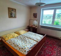Bedroom in a family house with a patterned carpet, furniture, and paintings on the wall.