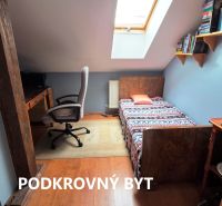 Attic room with a bed, chair, computer, and books, floor with wooden decor.