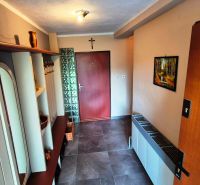 A hallway in a family house with a coat rack wall and tiles, a picture of nature on the wall.