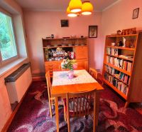 Dining room in a family house with wooden furniture and a large window.