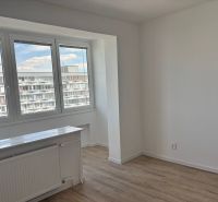 A bright room with large windows and a wooden decor floor in a 2-room apartment.