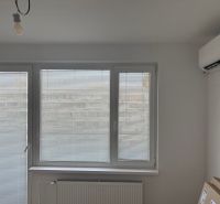 Interior of a 2-room apartment with air conditioning, horizontal blinds, and a radiator.