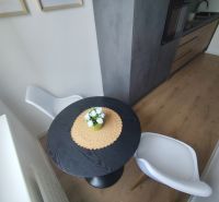 Dining area with a black table and white chairs in a three-room apartment.