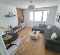 Living room in a three-room apartment with a wooden decor floor and a comfortable sofa.