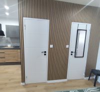 Doors and a kitchen with built-in appliances in a 3-room apartment with a wooden decor floor.