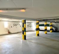 Parking in the basement of a building with numbered spaces and yellow-black columns.