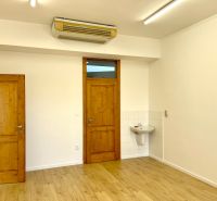 Offices with wooden doors, light walls, and a floor with a wooden design.