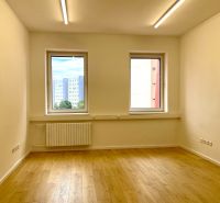 Empty office room with wood-patterned flooring and large windows.