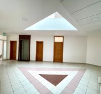 A bright office interior with doors and an elevator, floor with a geometric pattern.