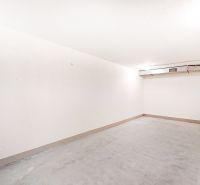 Empty garage interior with white walls and gray floor.