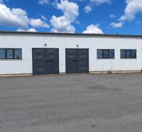 Warehouse and hall building in the village of Ličartovce, with large gates and an asphalt surface.