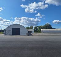 Warehouses and halls in Ličartovce with a blue sky and white clouds.
