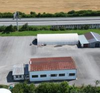 Warehouses and halls in Ličartovce near the highway, with parking and adjacent greenery.