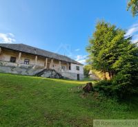 A family house in Dobroč with an extensive lawn and trees on a sloping plot.