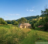 A family house in Dobroč surrounded by nature and green meadows under a blue sky.